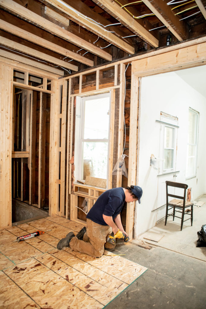 Carpenter installing subfloor with a power tool 