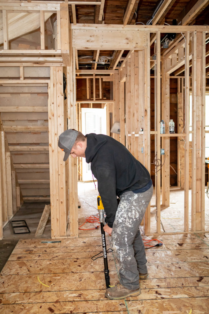 A third carpenter, working on the final touches of the subfloor installation