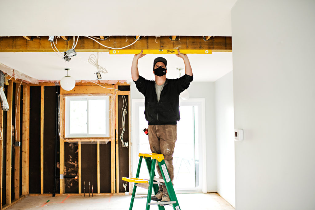 Carpenter measuring overhead beam 