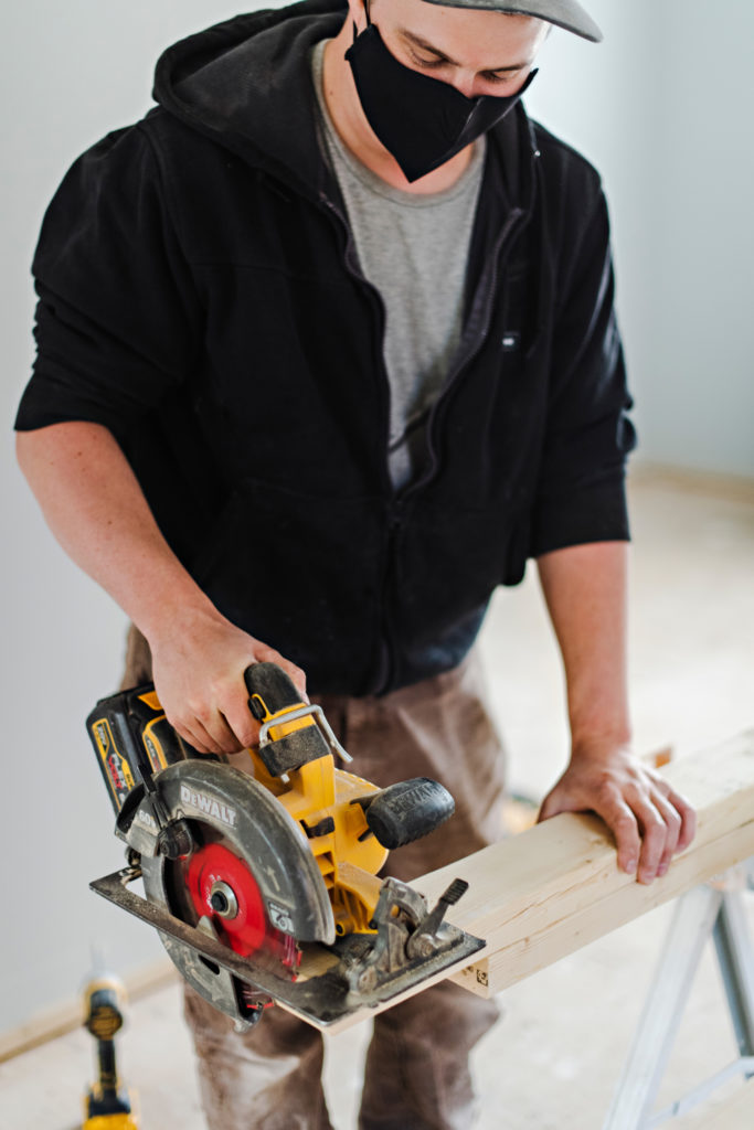 Carpenter cutting a plank of wood with electric saw 